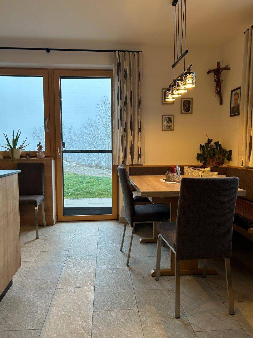 Essbereich mit Holztisch, Eckbank und Zugang zum Garten oder zur Terrasse.