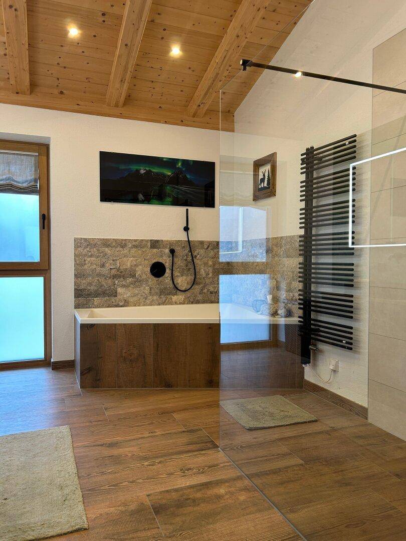 Modernes Badezimmer mit Holzbalkendecke, Badewanne und begehbarer Dusche.