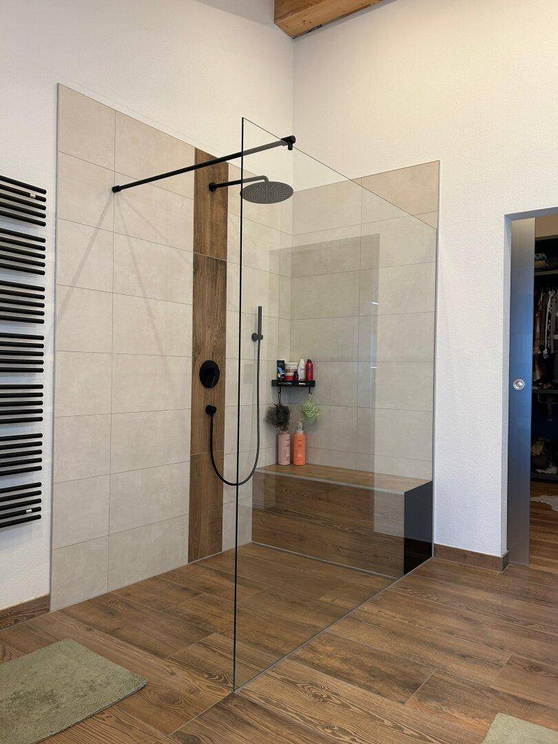 Geräumige, moderne begehbare Dusche mit Glaswand und Holzboden.