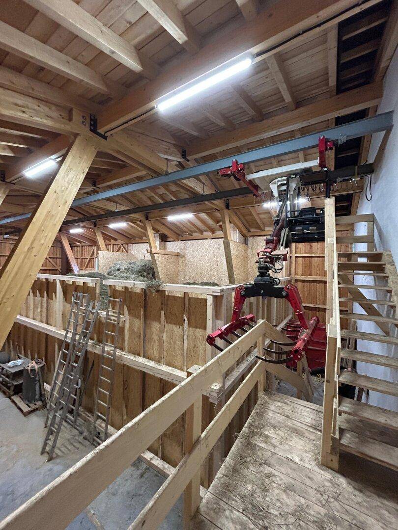 Heuboden mit Förderanlage und Holztreppe in einem landwirtschaftlichen Gebäude.