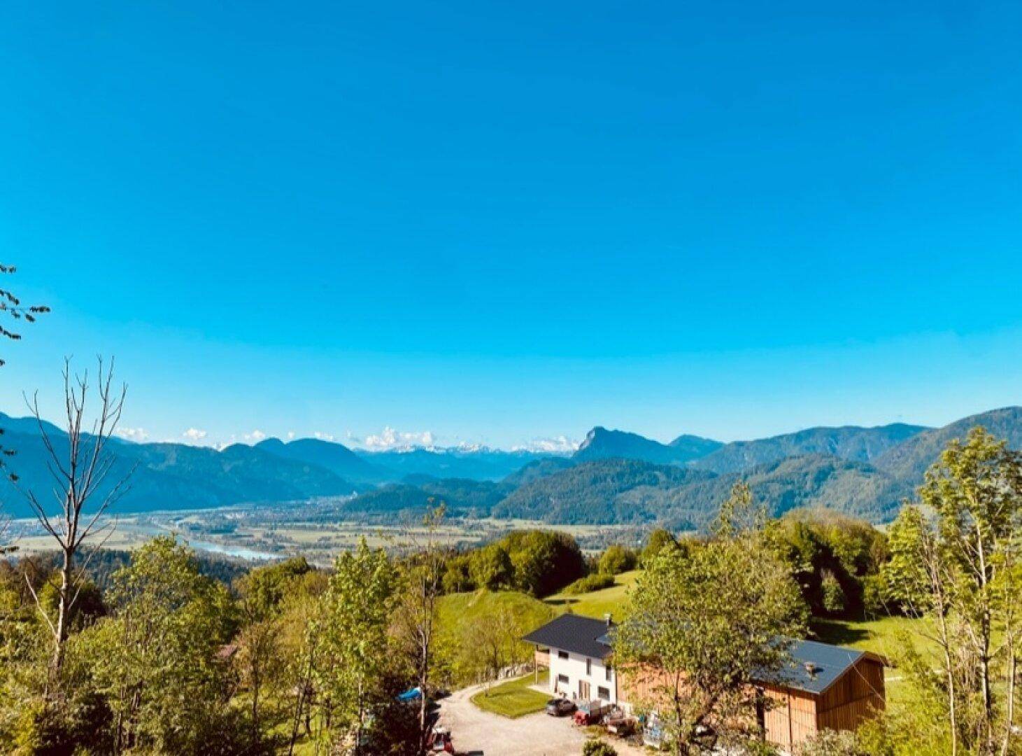 Weitläufiges Anwesen in einer grünen Hügellandschaft mit Fernblick auf Berge und Tal.