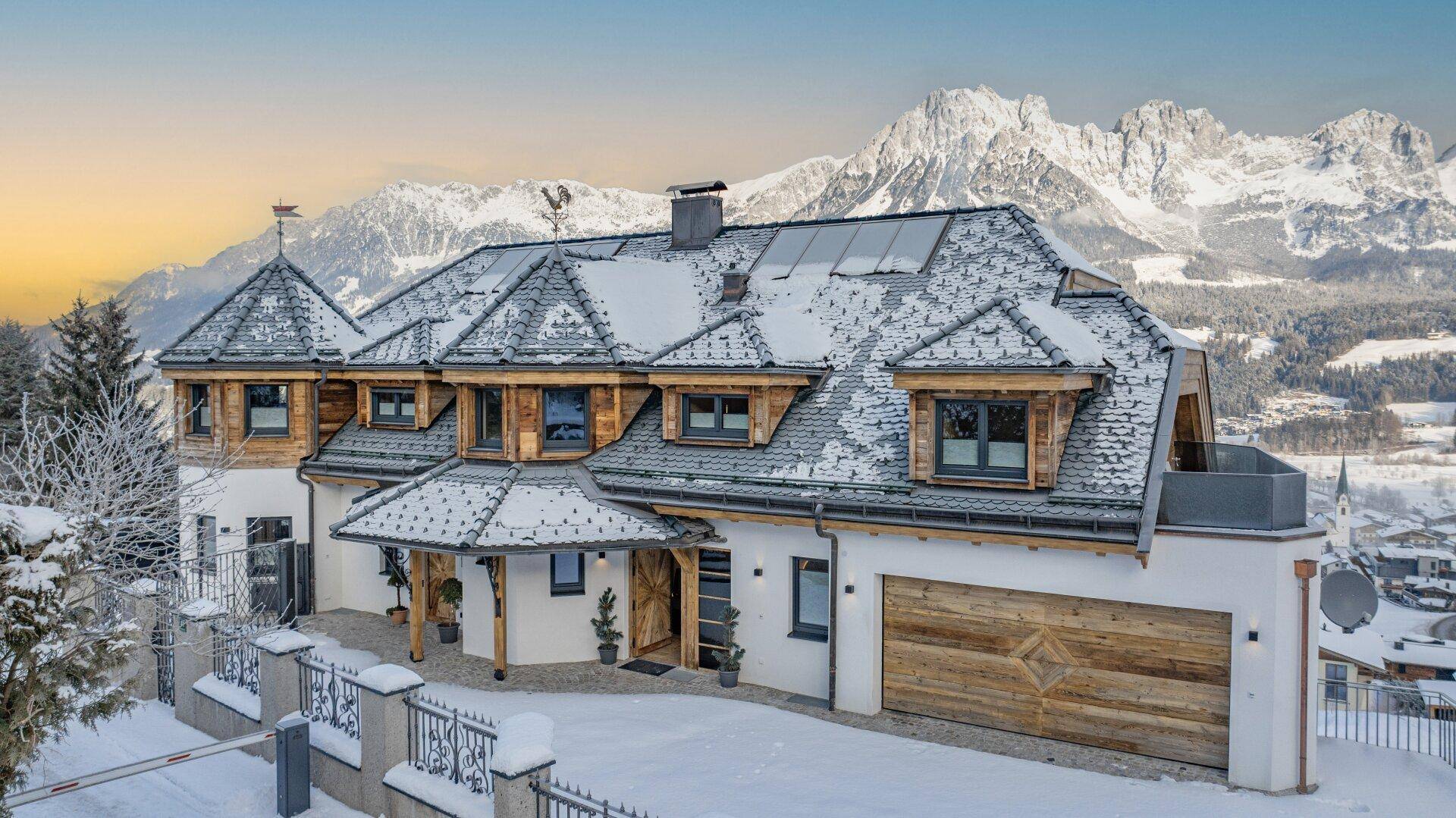 Luxuriöse Villa in verschneiter Berglandschaft mit Solaranlage auf dem Dach.