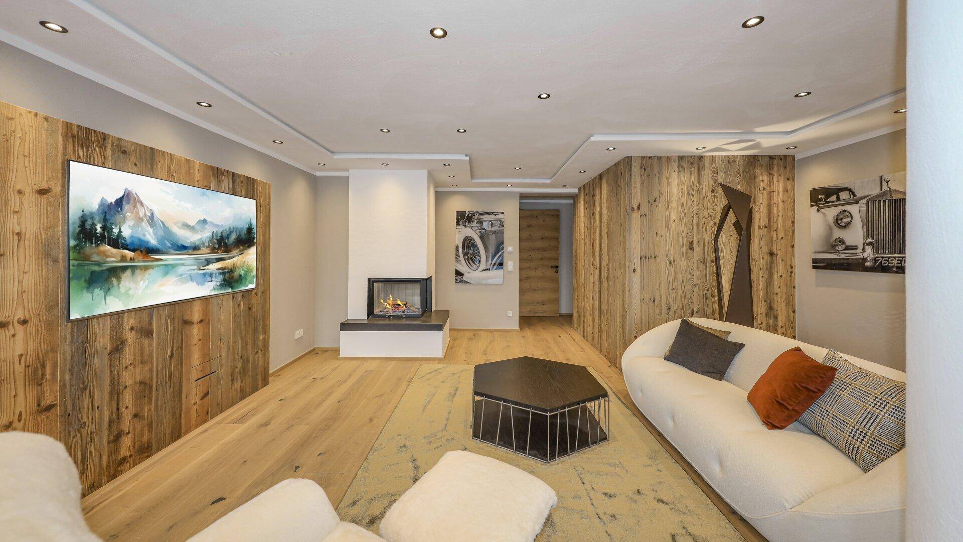 Geräumiges Wohnzimmer mit Holzwänden, Kamin und großem Flachbildfernseher.