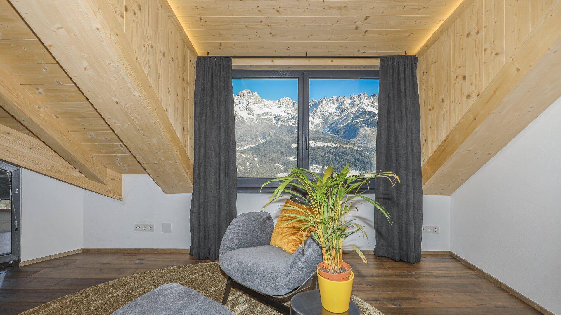 Gemütlicher Sitzbereich im Schlafzimmer mit Bergblick durch große Fenster.