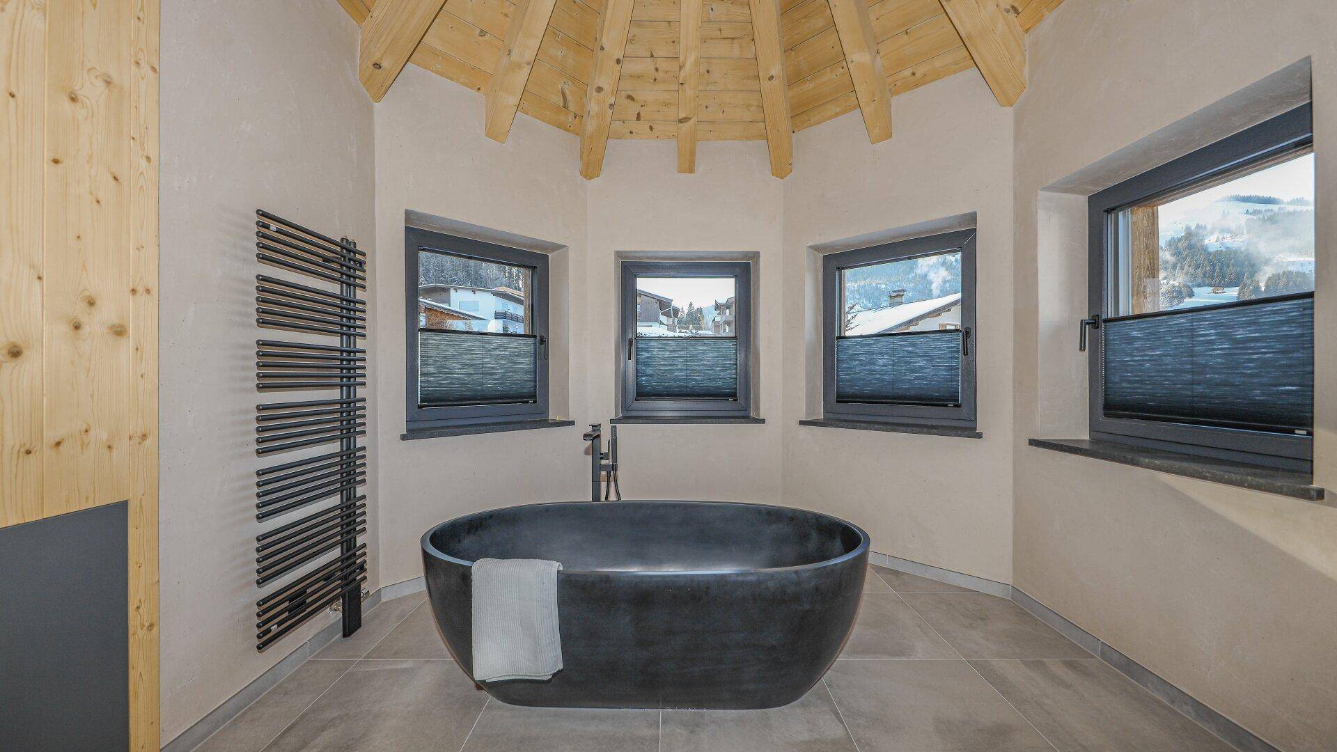 Einzigartiges Badezimmer mit freistehender Badewanne, beheiztem Handtuchhalter und mehreren Fenstern.