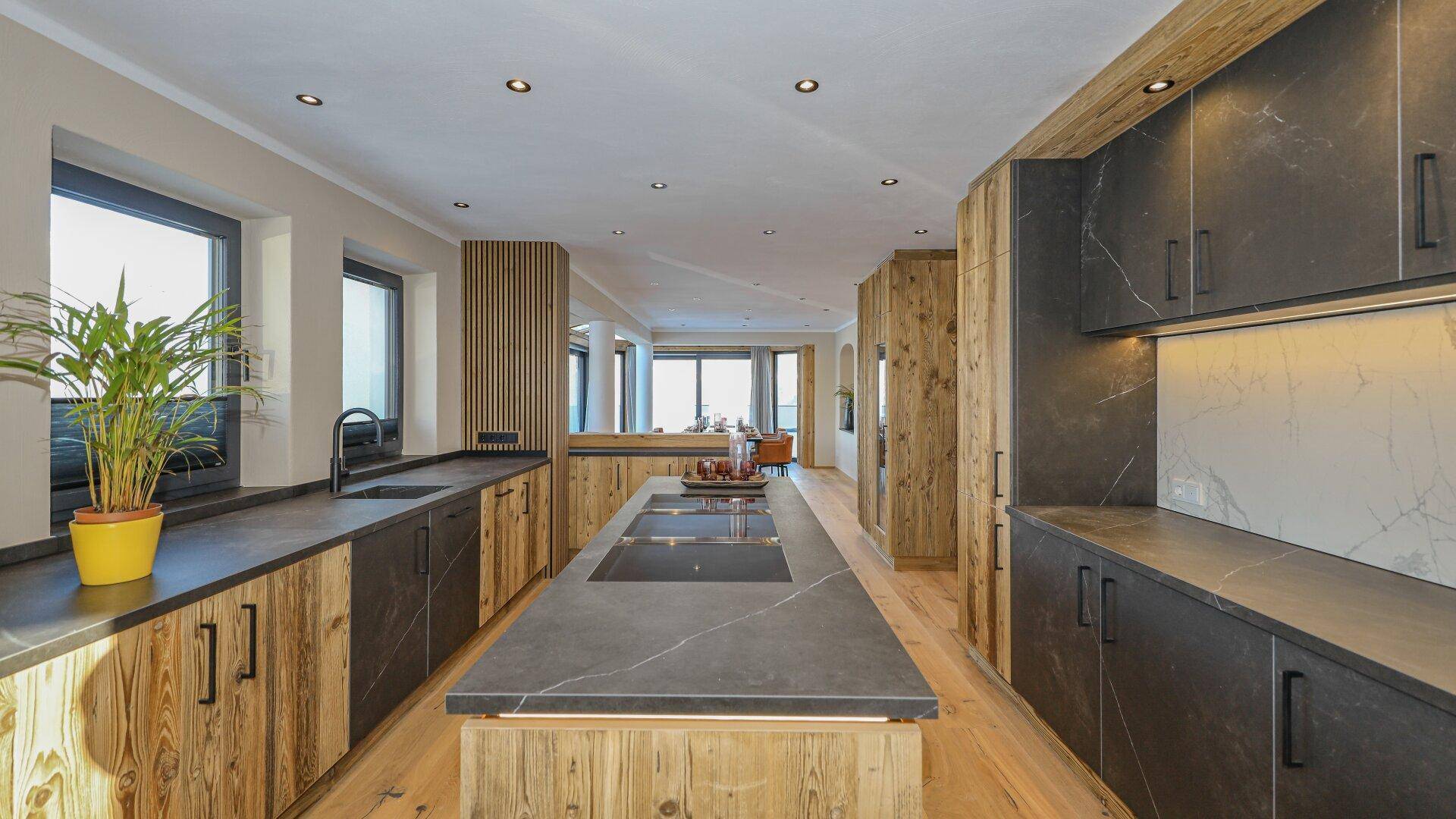 Moderne Küche mit dunklen Arbeitsplatten, Holzelementen und integrierten Geräten.