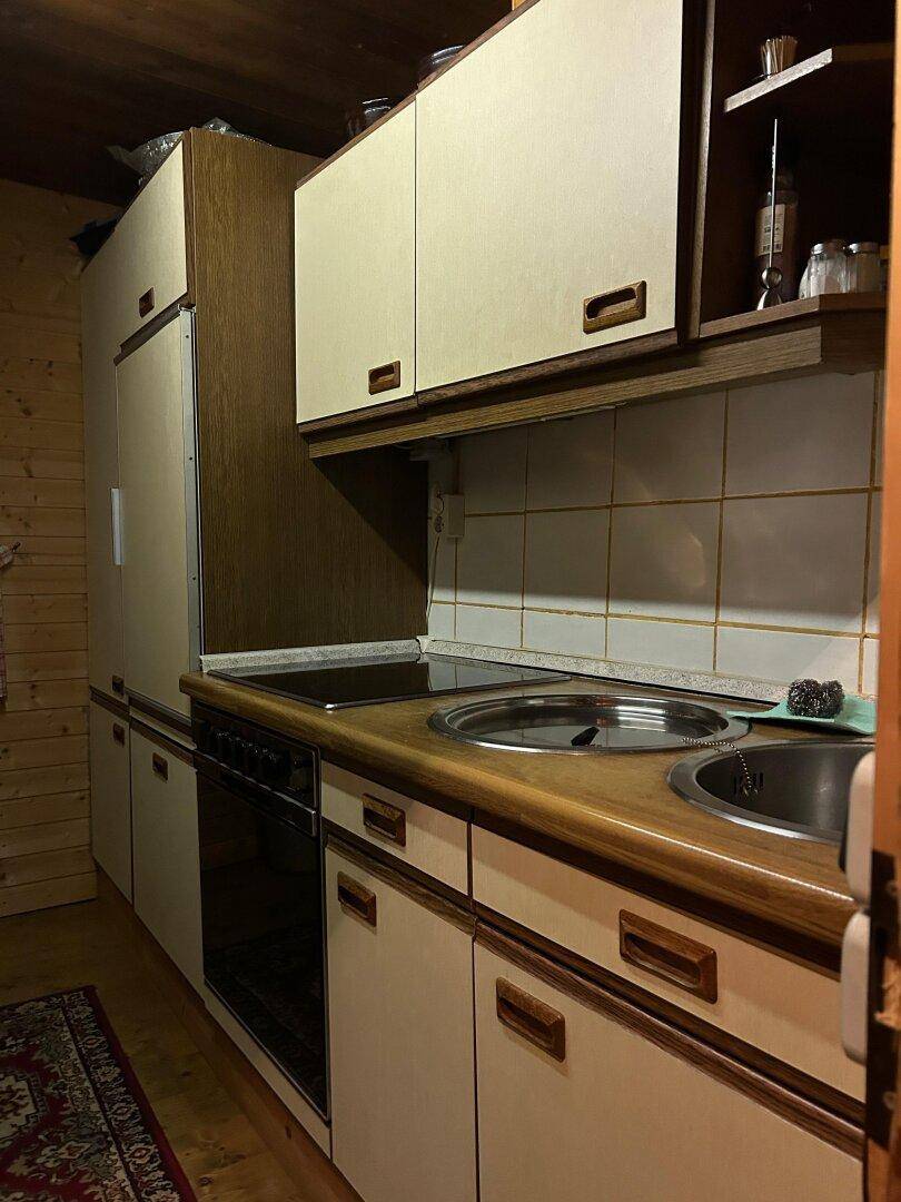 Rustikale Küche mit älteren Einbauschränken, Holztheke und integrierten Spülbecken.