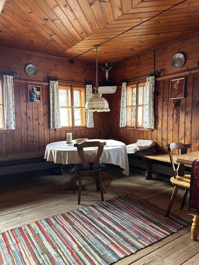 Gemütlicher Essbereich im Landhausstil mit Holztäfelung, kleinem Tisch und gestreiftem Teppich.