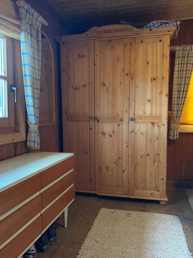 Schlafzimmer mit Holzwänden, Holzschrank und Kommode, typisch für den Landhausstil.