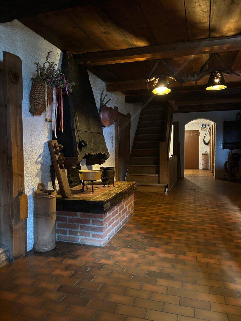 Geräumiger Flur mit Terrakotta-Fliesenboden, traditionellem Kamin und Holztreppe.