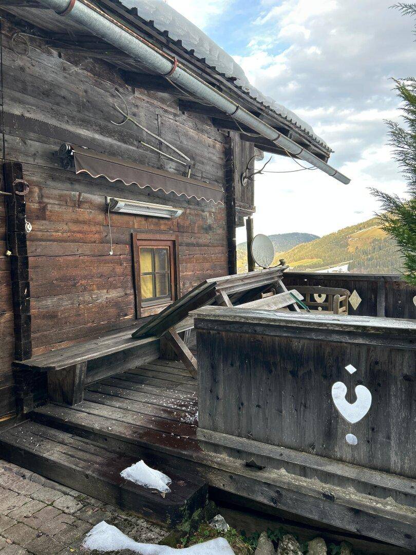 Rustikaler Holzbalkon mit Sitzgelegenheiten und Blick auf die umliegende Berglandschaft.