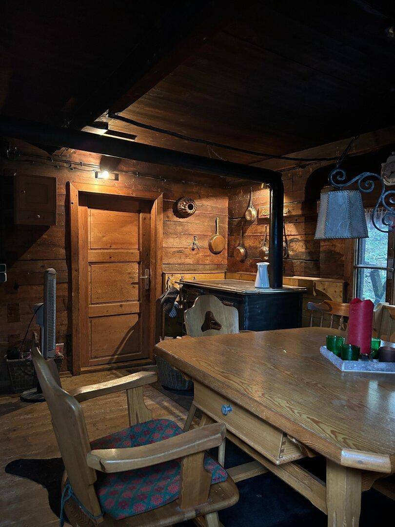 Gemütlicher Essbereich mit Holztisch, Stühlen und einem traditionellen Holzofen.