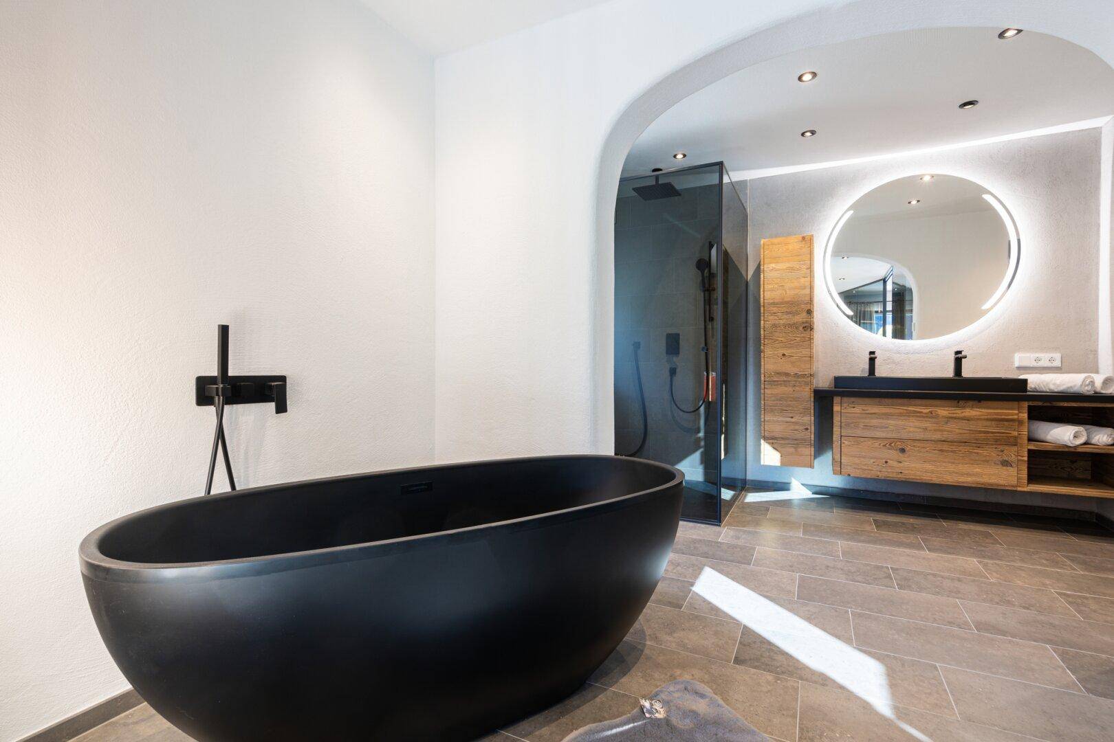 Modernes Badezimmer mit freistehender schwarzer Badewanne, begehbarer Dusche und Doppelwaschbecken.
