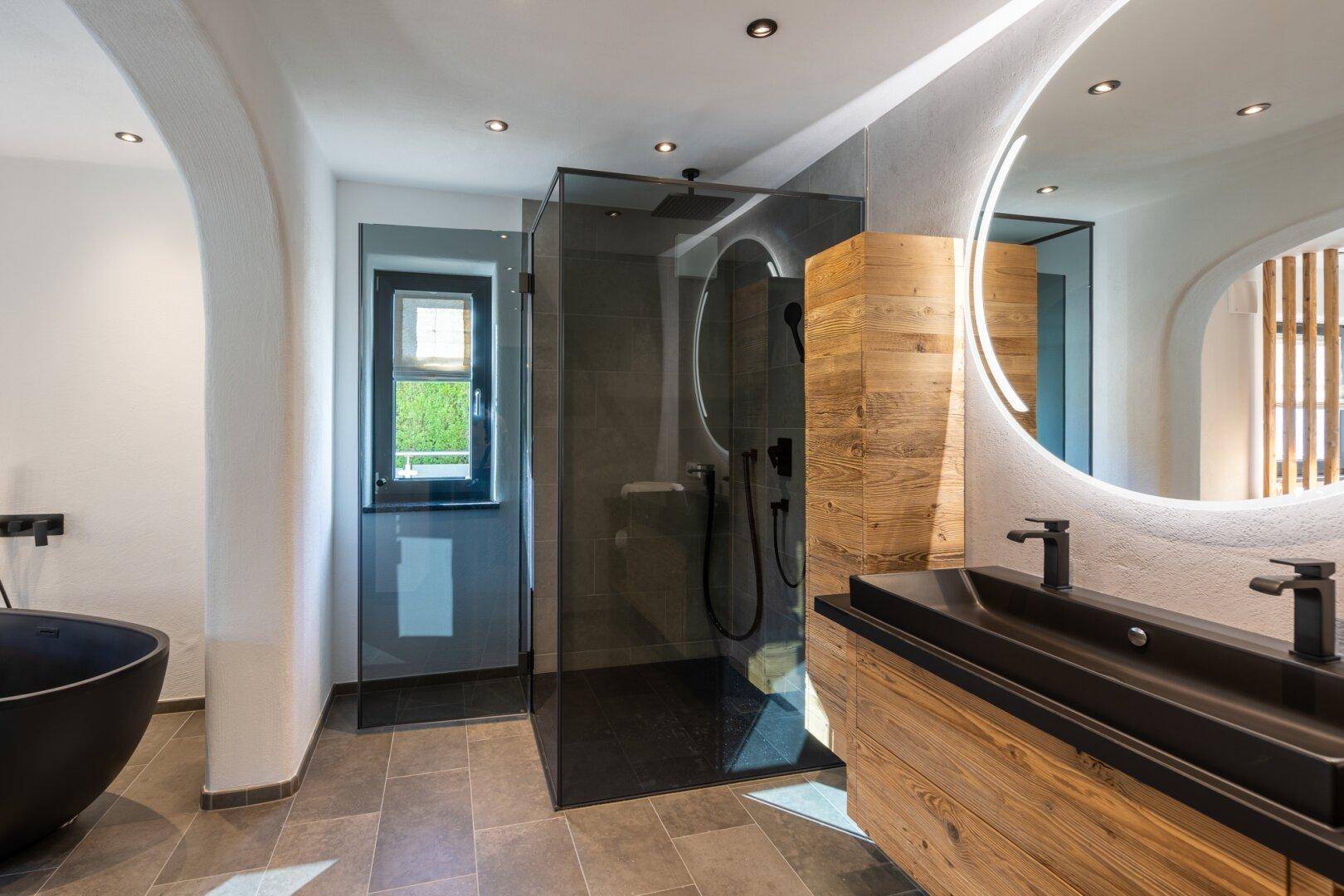 Stilvolles Badezimmer mit Doppelwaschbecken, begehbarer Dusche und indirekter Beleuchtung.