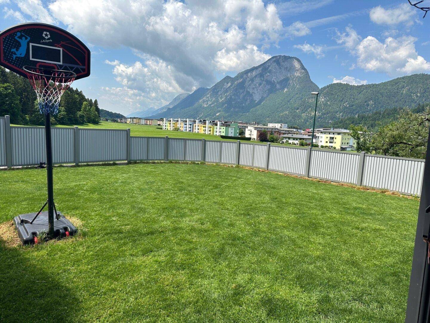Weitläufiger Garten mit Rasenfläche und Basketballkorb, bietet einen beeindruckenden Bergblick.