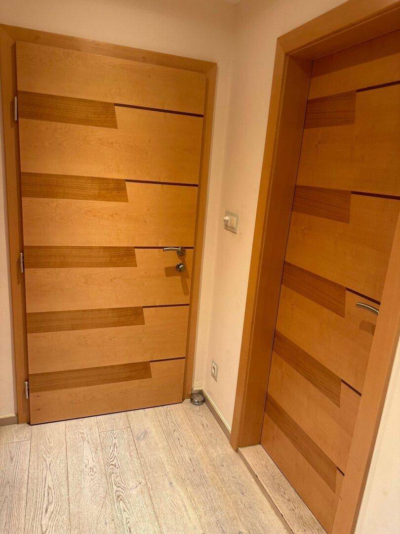 Moderner Flur mit Holzböden und stilvollen Holztüren, die zu verschiedenen Räumen führen.