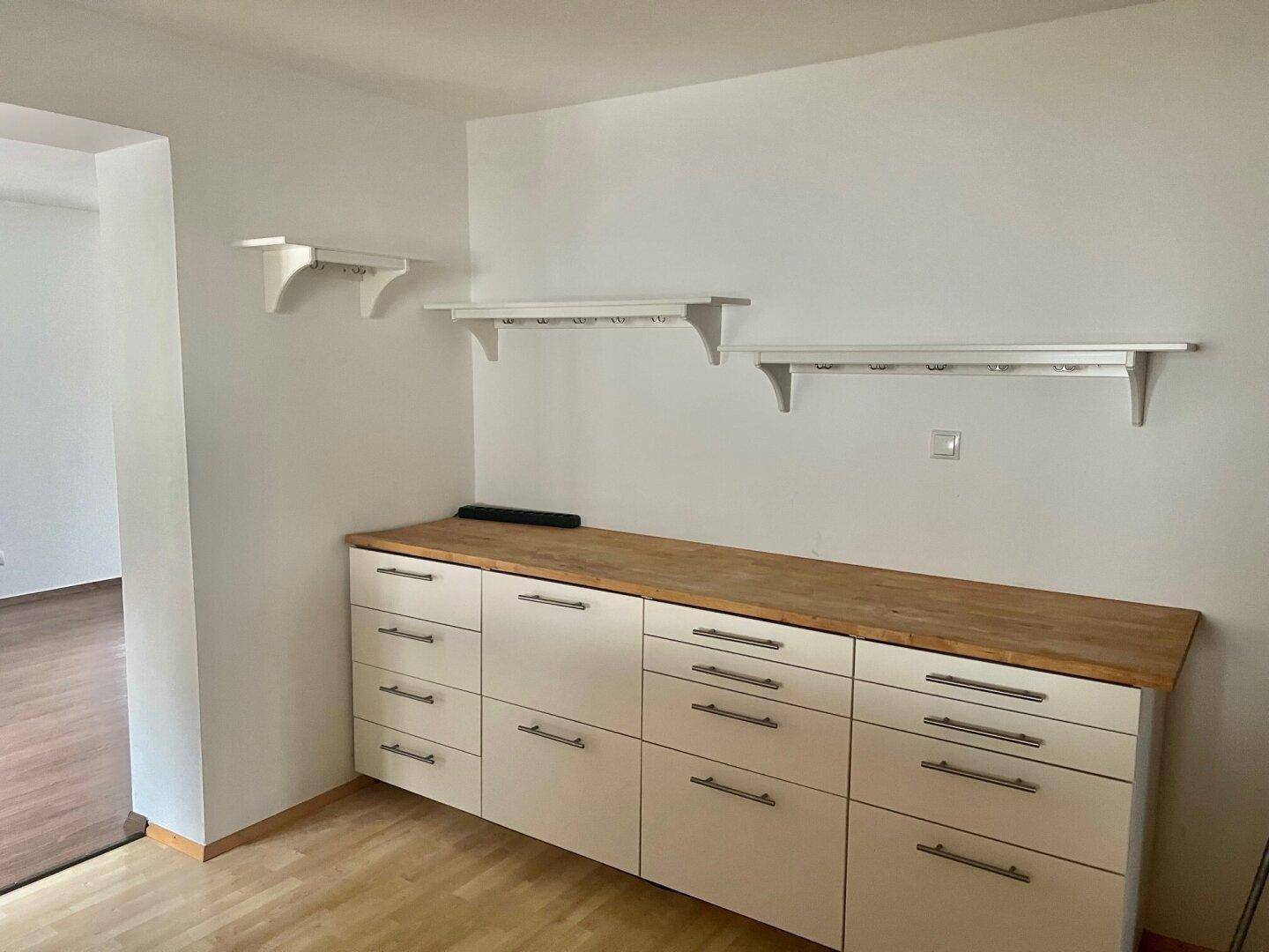 Heller Raum mit Holz-Arbeitsplatte und weißen Unterschränken, ideal als zusätzliche Küchenzeile oder Abstellraum.