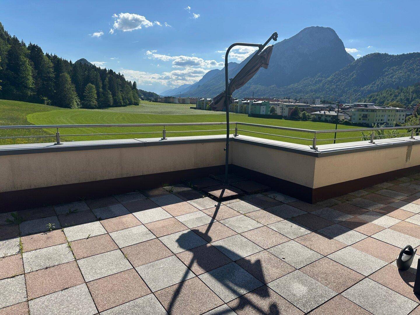 Große Dachterrasse mit Fliesenboden und weitem Blick auf die umliegende Landschaft und Berge.