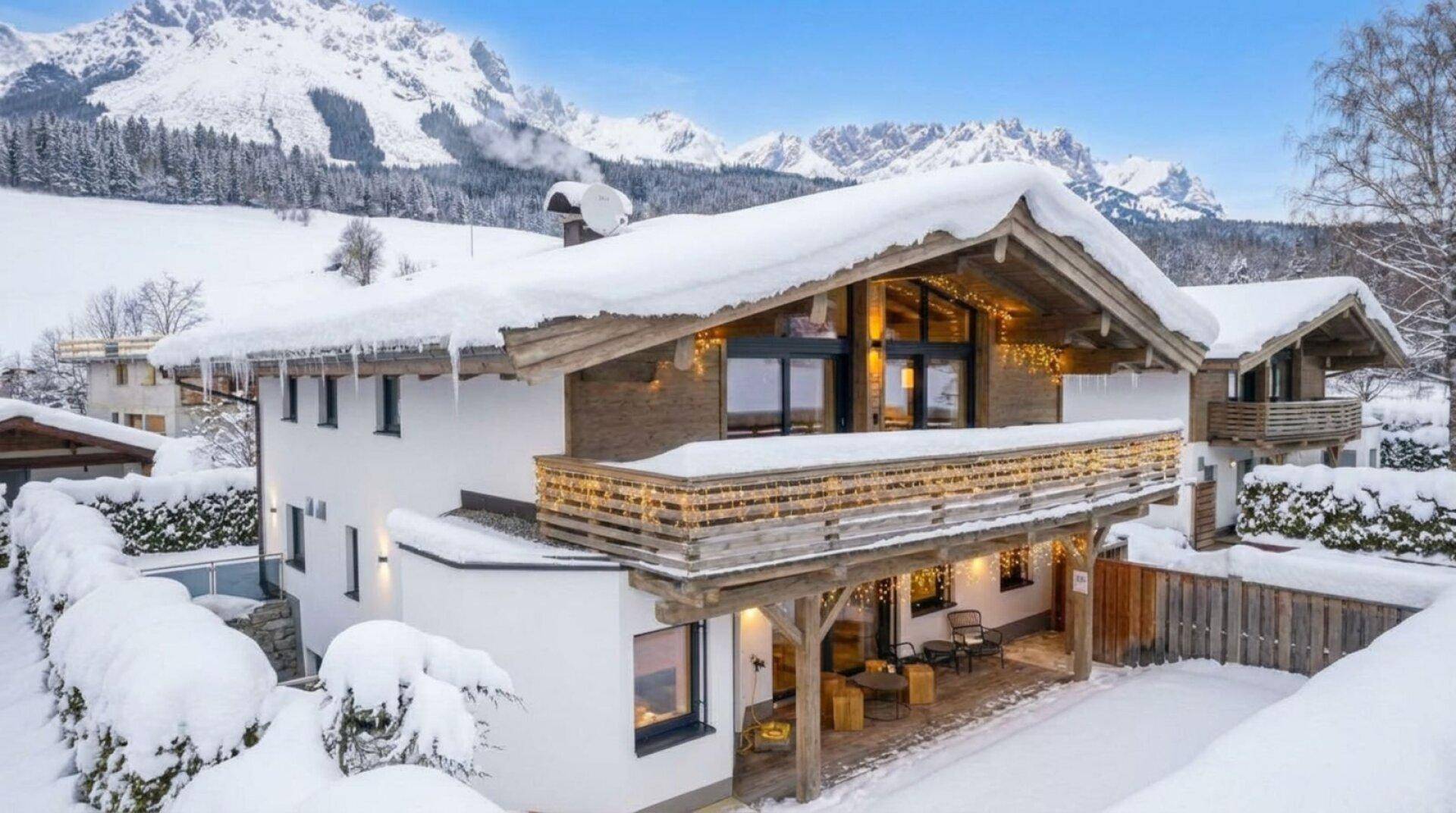 Luxuriöses Chalet im Winter mit verschneiter Terrasse, Balkon und Panoramablick auf die Berge.