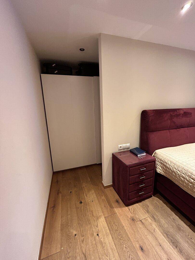 Schlafzimmerbereich mit Holzboden und einem offenen Bereich, der als begehbarer Kleiderschrank genutzt werden könnte.