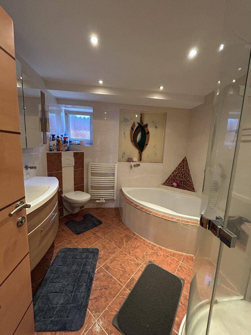Geräumiges Badezimmer mit Eckbadewanne, separater Dusche und beheiztem Handtuchhalter.