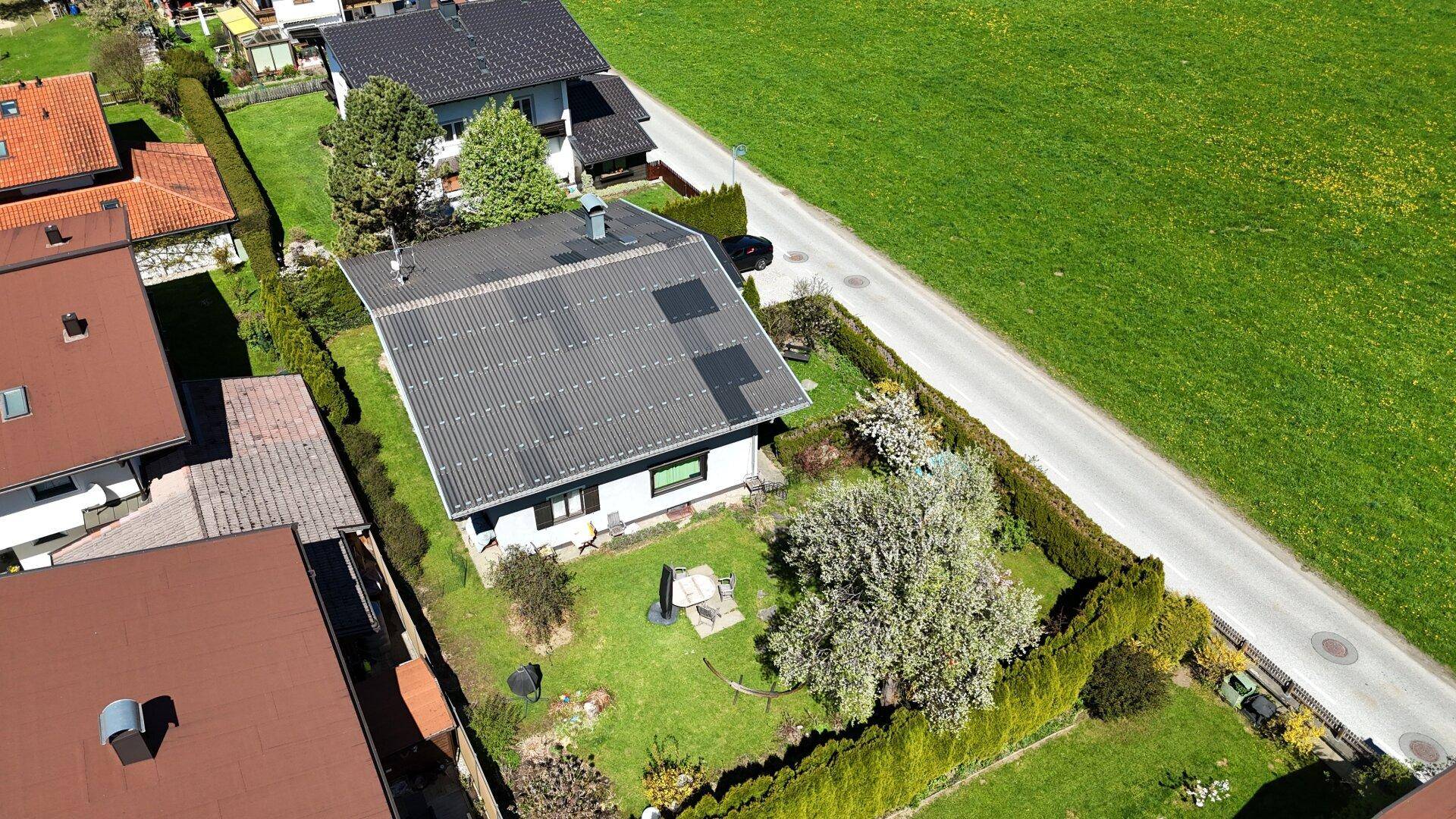 Luftaufnahme des Hauses mit Solaranlage auf dem Dach, Garten und angrenzenden Feldern.