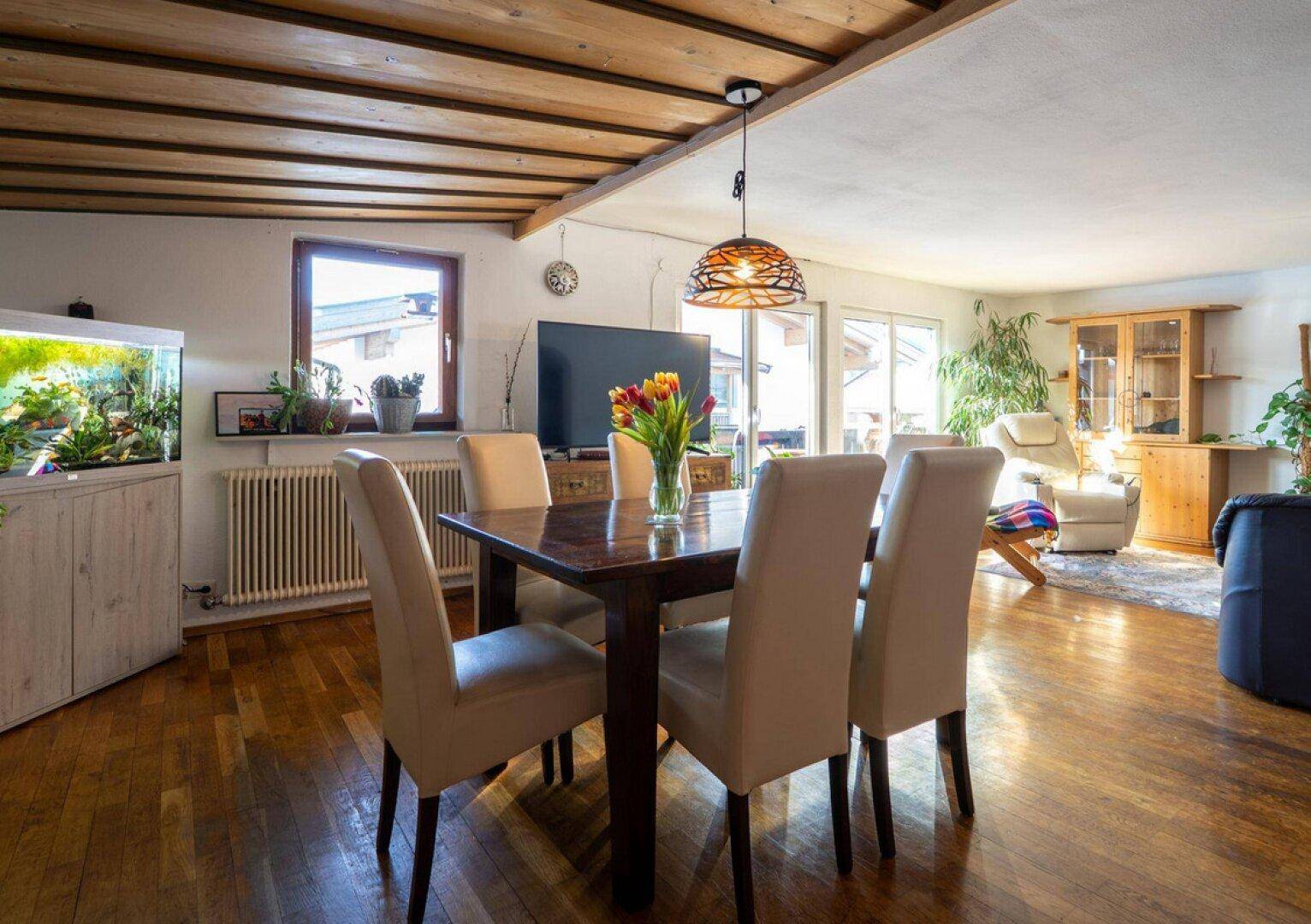 Heller Wohn- und Essbereich mit Holzboden, Esstisch und Zugang zur Terrasse.