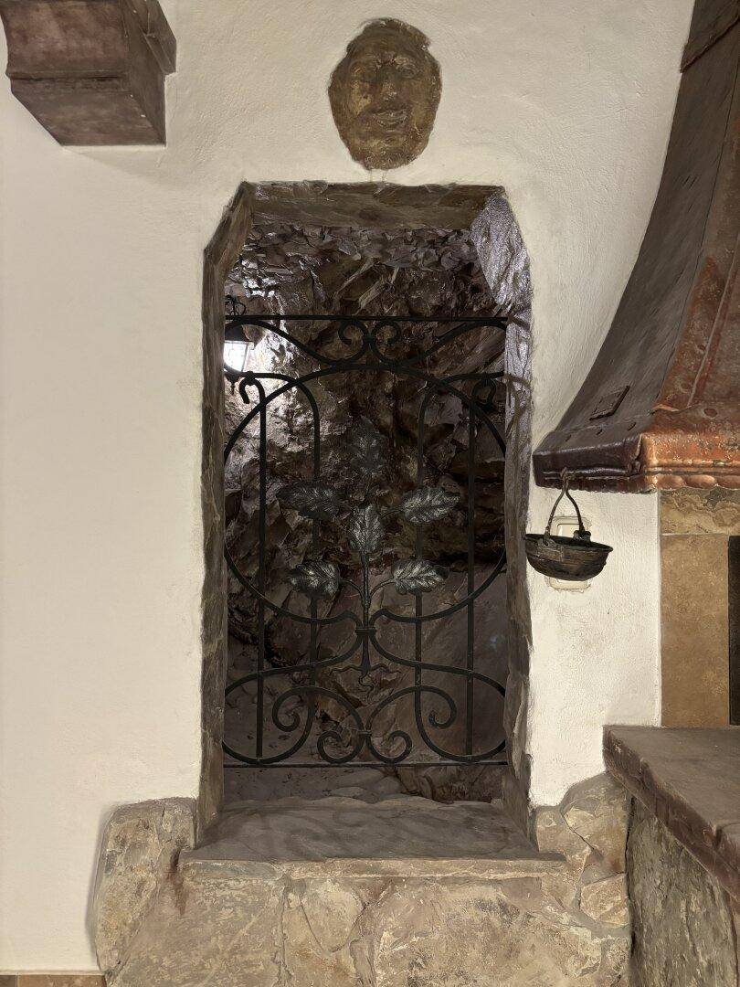 Rustikaler Weinkeller-Eingang mit Steinmauern und einem kunstvollen schmiedeeisernen Tor.