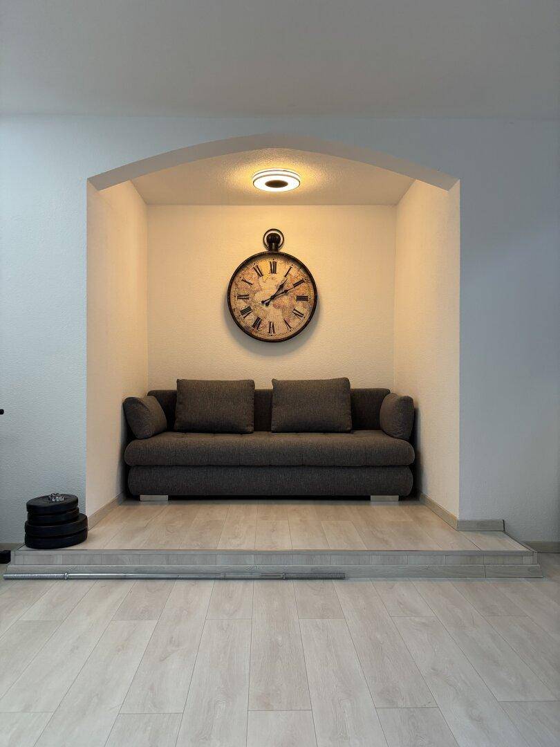 Gemütliche Sitzecke in einer Nische mit Sofa und dekorativer Wanduhr.