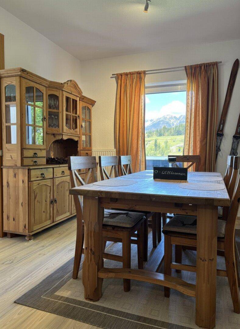 Gemütlicher Essbereich mit rustikalen Holzmöbeln und einem Fenster mit Bergblick.