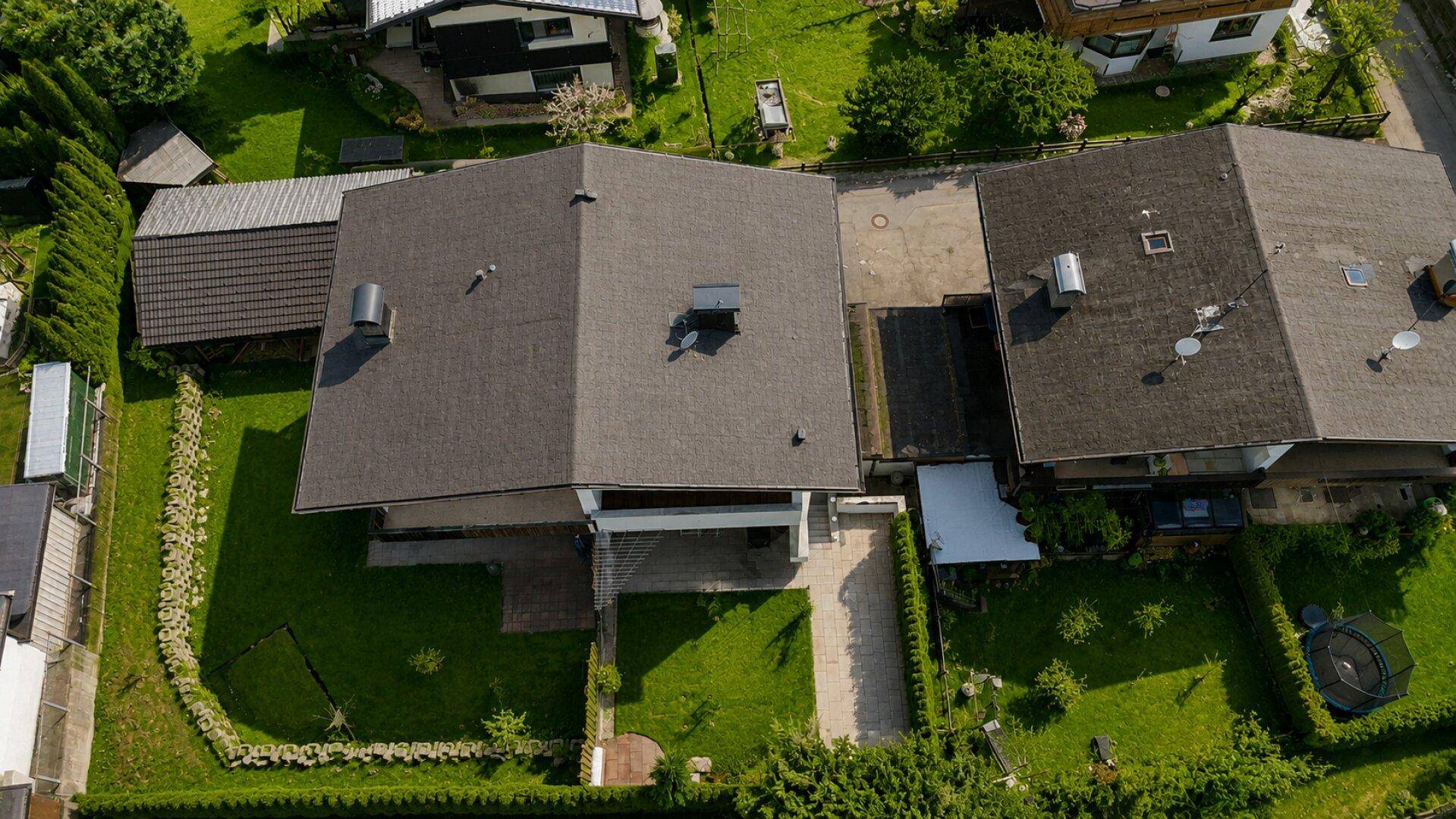 Draufsicht auf das Satteldach des Hauses und die umliegenden Grundstücke mit viel Grünfläche.