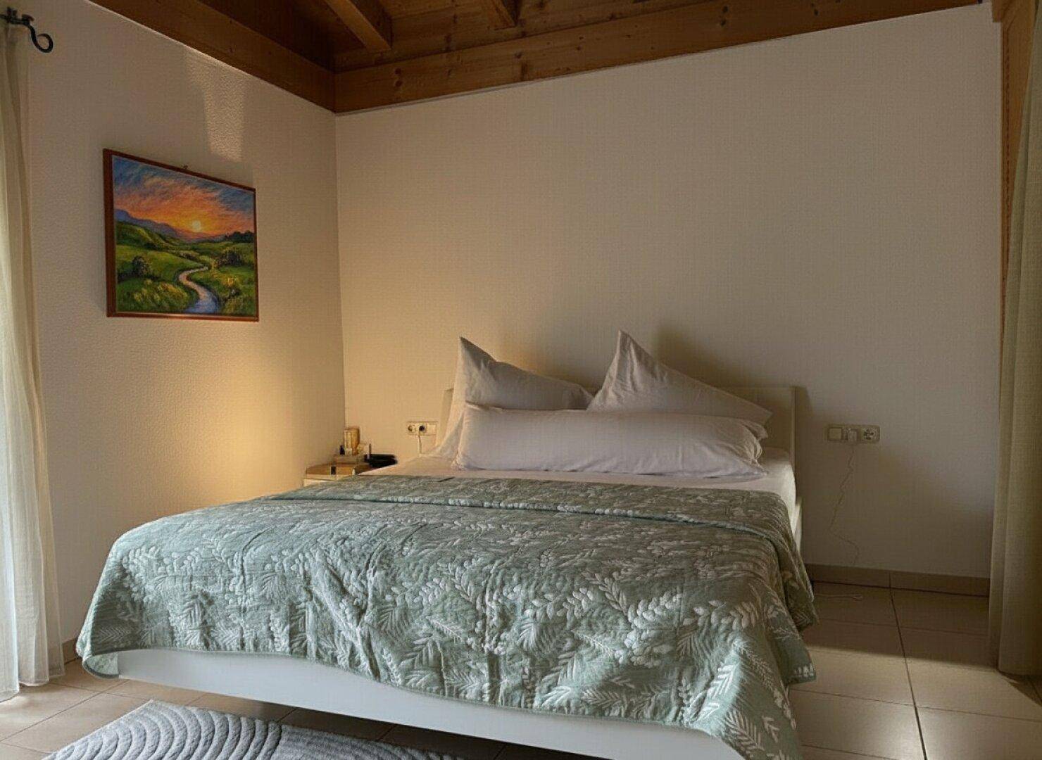 Ruhiges Schlafzimmer mit Doppelbett, Fliesenboden und Blick ins Grüne.