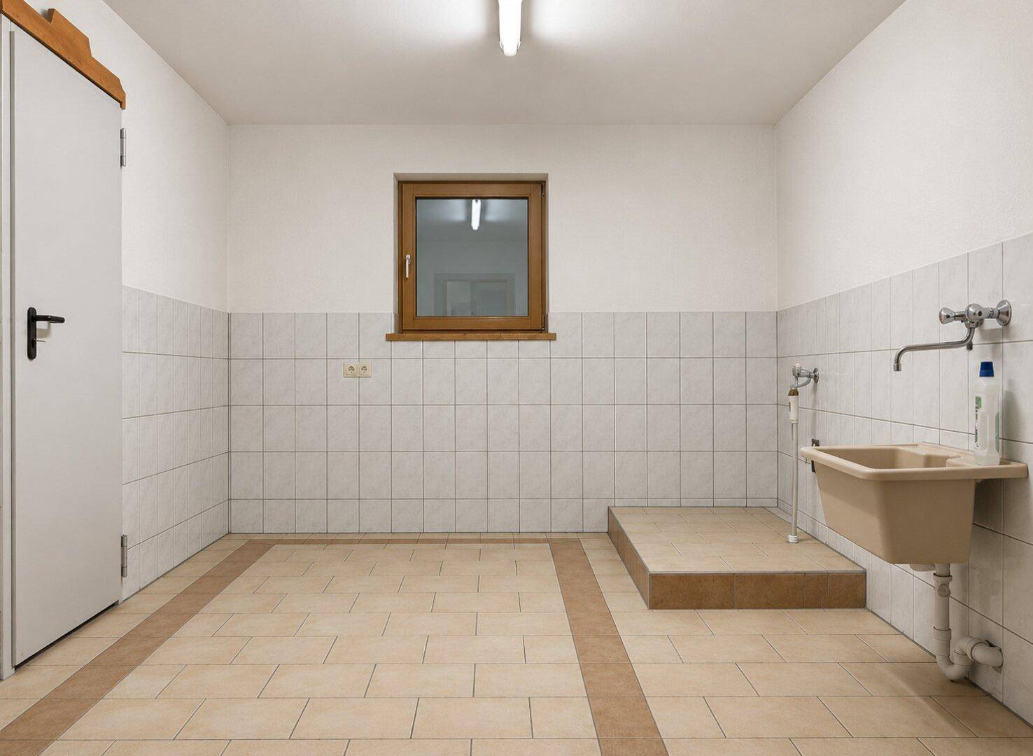 Praktischer Hauswirtschaftsraum mit Fliesenboden, Waschbecken und Fenster.