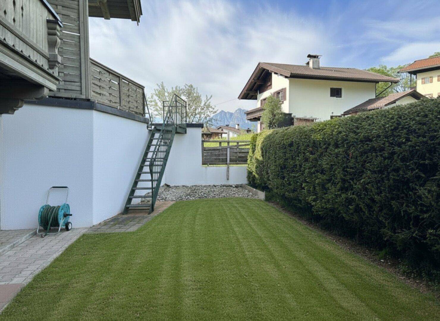 Hinterhof mit gepflegtem Rasen und einer Außentreppe zum oberen Bereich.