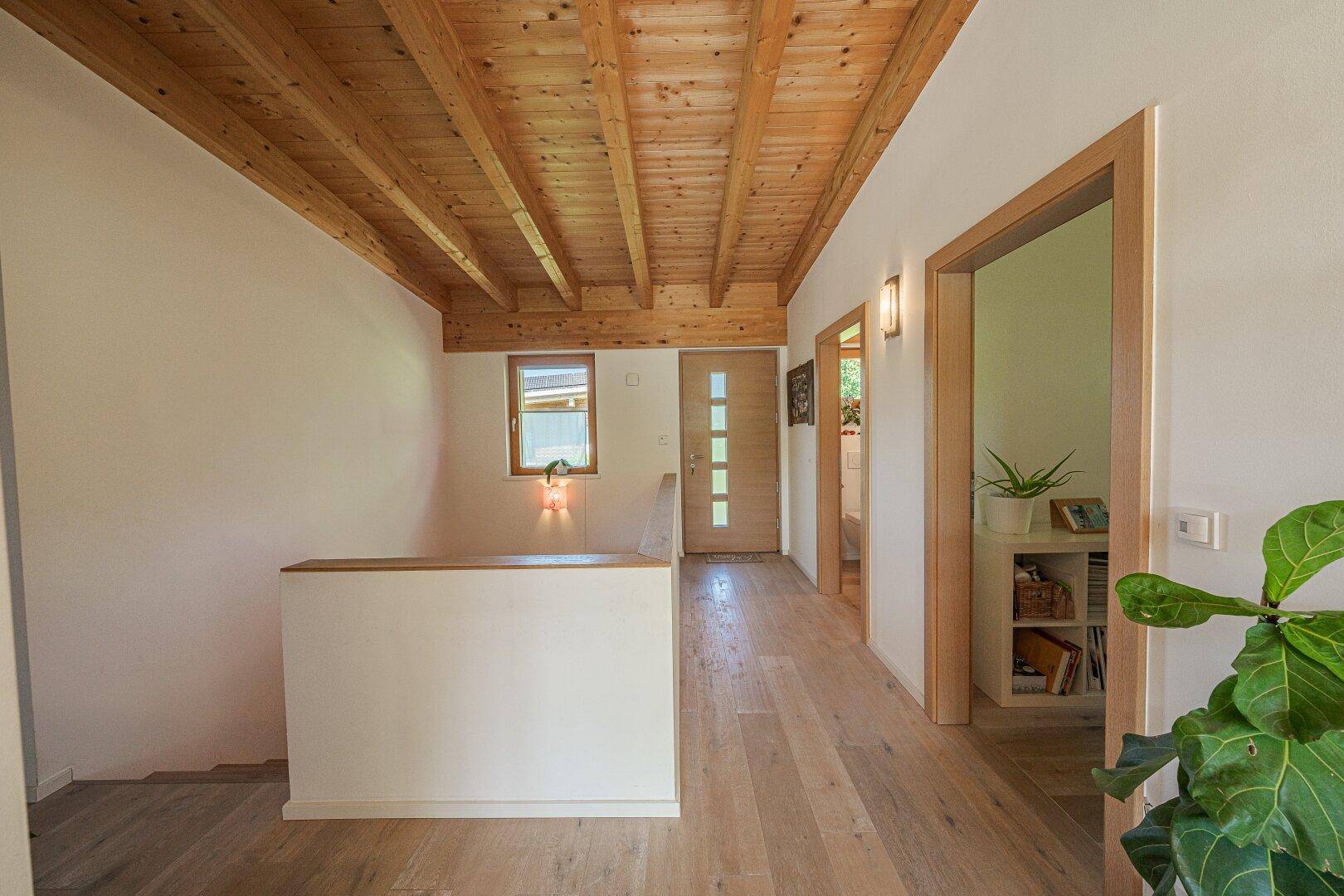 Heller Flur mit Holzbalkendecke, Holzfußboden und Zugang zu weiteren Räumen.