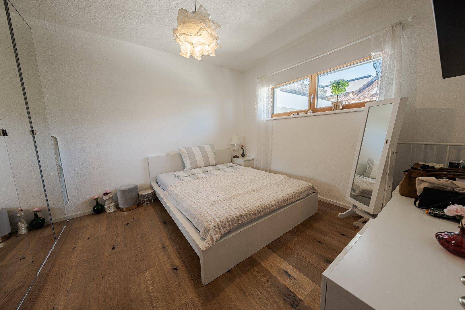 Helles Schlafzimmer mit Doppelbett, Kleiderschrank und Holzfußboden.