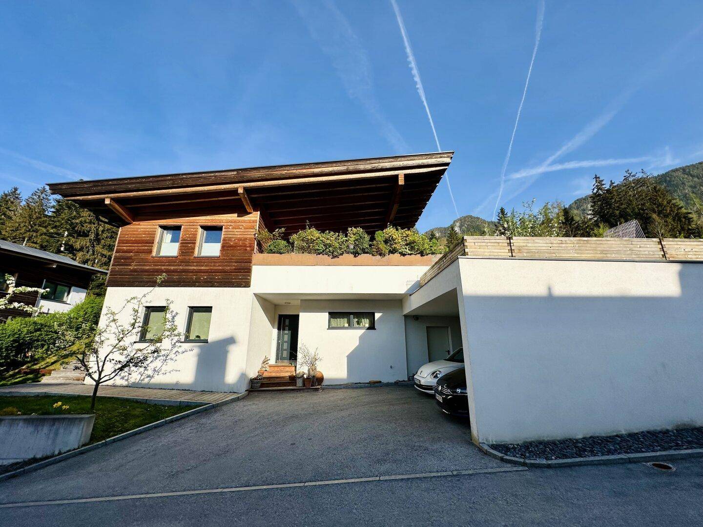 Modernes Wohnhaus mit Carport, weißer Fassade und Holzelementen.