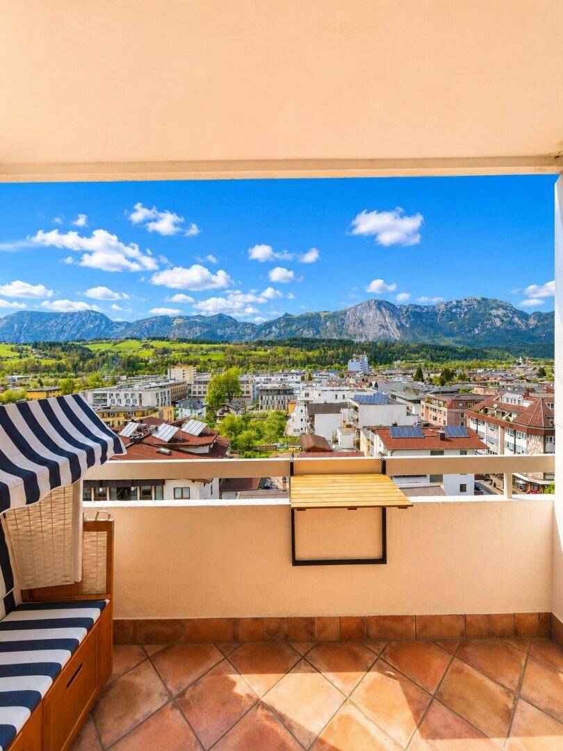 Geräumiger Balkon mit Strandkorb und weitem Blick auf die Stadt und die umliegenden Berge.