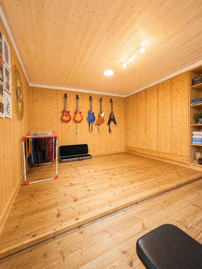 Hobbyraum mit Holzwänden, Holzboden und Gitarren an der Wand, ideal für Musikliebhaber.