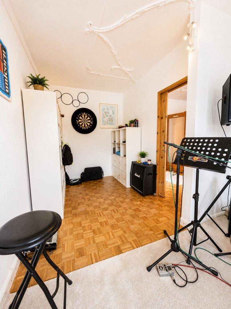 Raum mit Parkettboden, Dartscheibe und Musikinstrumenten, vielseitig nutzbar.