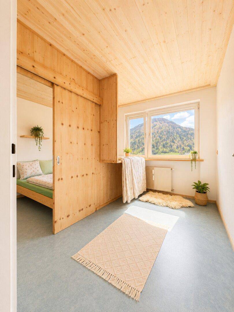 Helles Schlafzimmer mit Holzwänden, Holzboden und Schiebetür zu einem weiteren Schlafbereich.