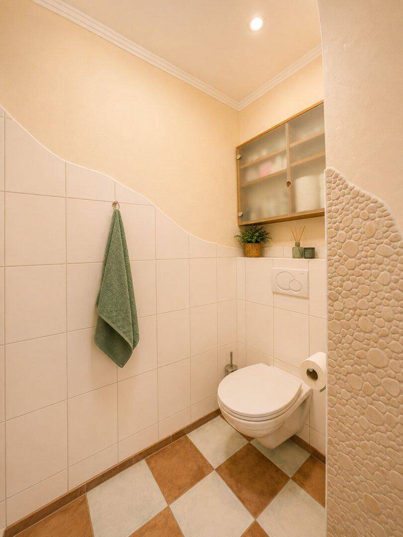 Separates WC mit Wandtoilette, Spiegelschrank und Schachbrettmuster-Fliesenboden.
