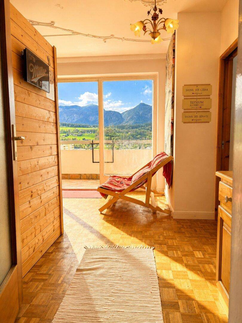 Heller Eingangsbereich mit Parkettboden und Zugang zu einem Balkon mit Bergblick.