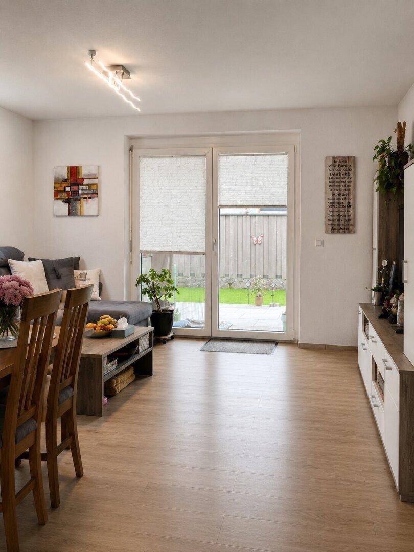 Helles Wohnzimmer mit Zugang zum Garten, Laminatboden und moderner Einrichtung.