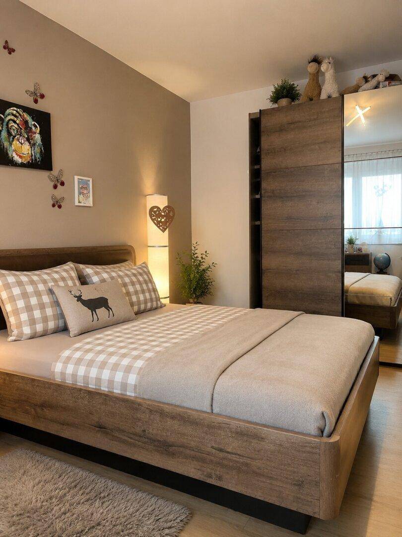 Gemütliches Schlafzimmer mit Holzbett, Spiegelschrank und warmen Brauntönen.