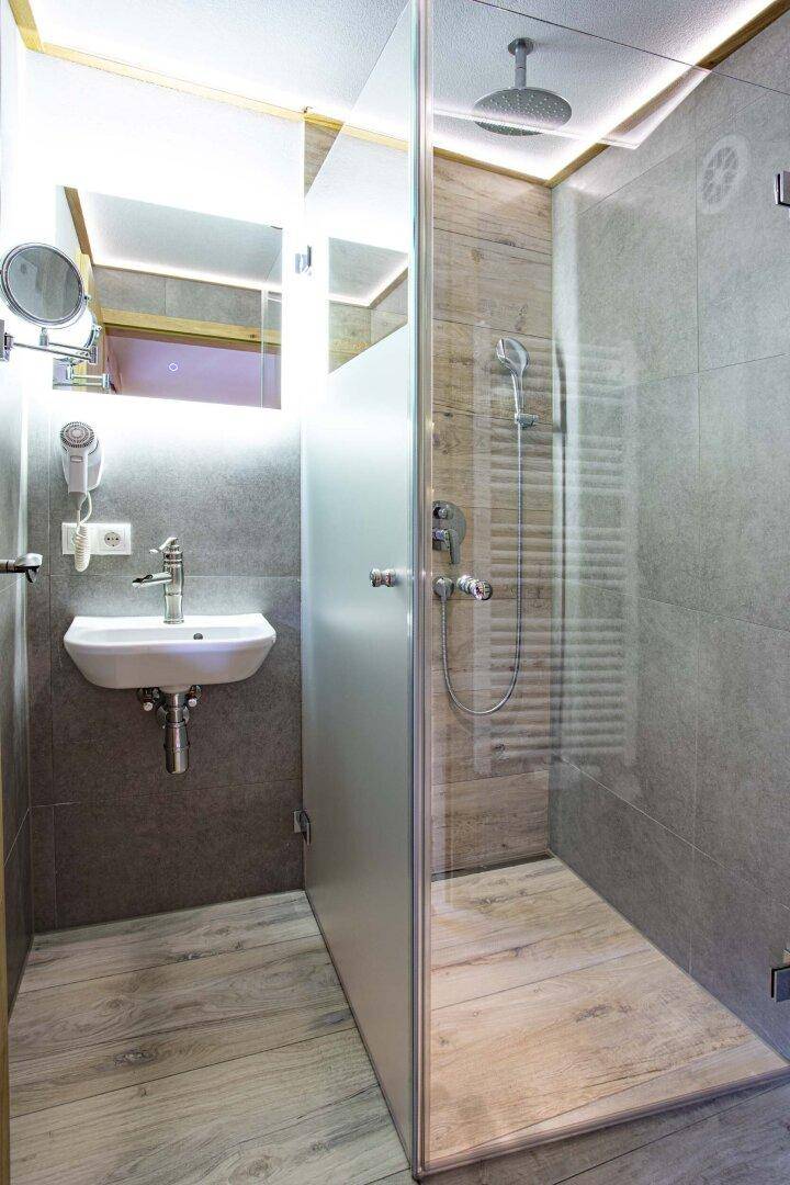 Modernes Badezimmer mit begehbarer Dusche, Regenbrause und Holzoptik-Fliesen.