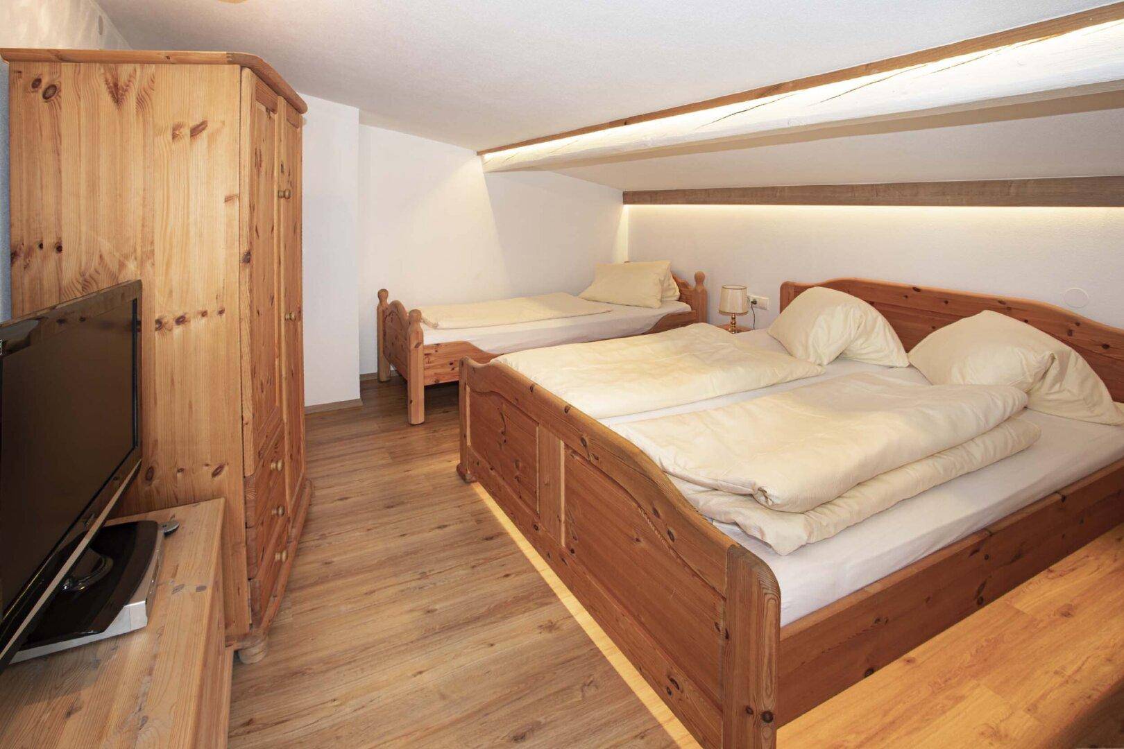 Geräumiges Schlafzimmer mit Doppelbett, Einzelbett und Holzmöbeln.