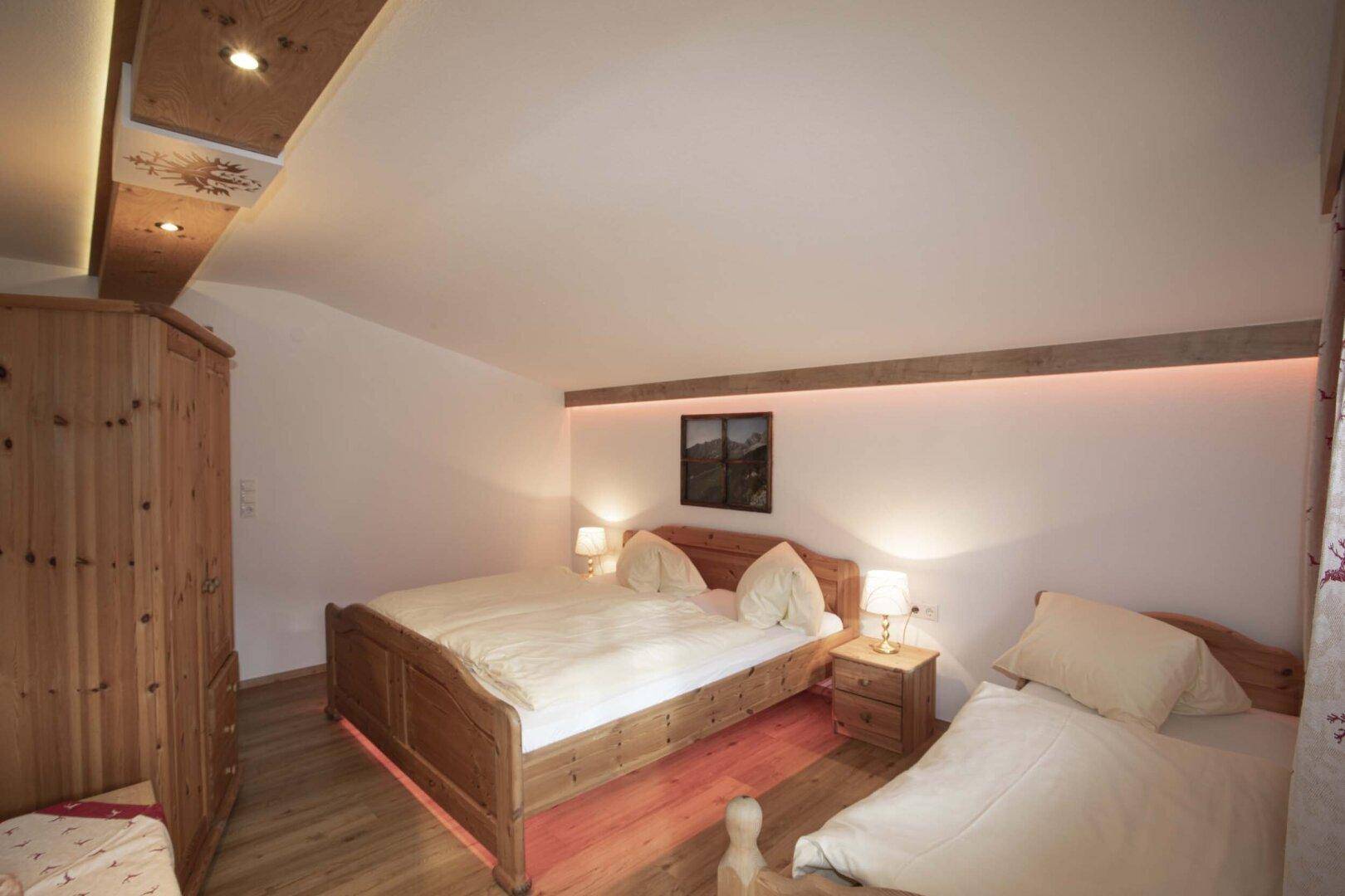 Schlafzimmer mit Doppelbett, Holzboden und indirekter Beleuchtung.