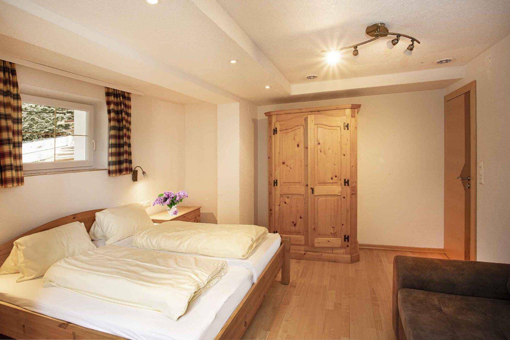 Gemütliches Schlafzimmer mit Doppelbett, Holzschrank und Holzboden.