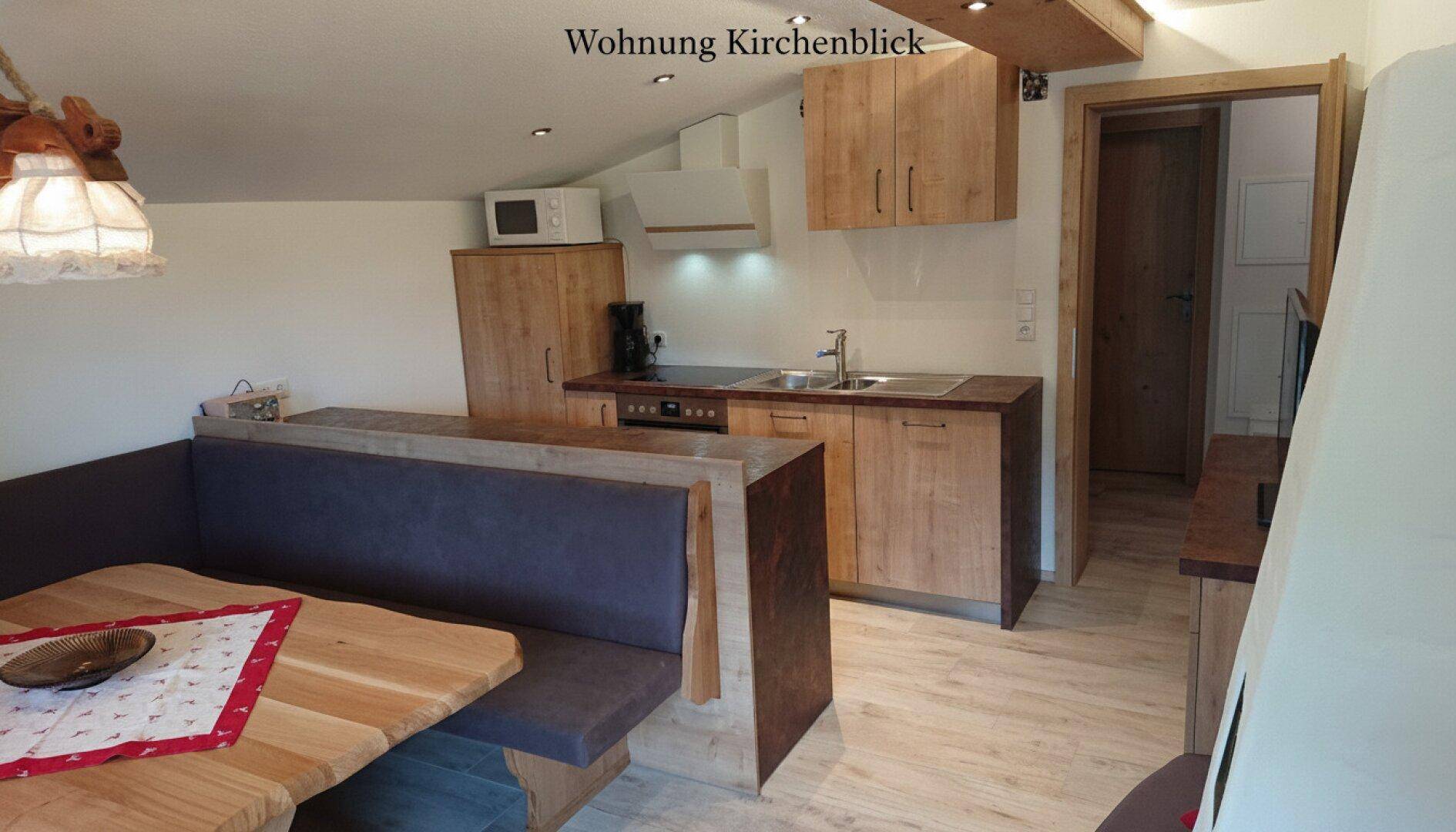 Offene Küche mit Essbereich, Holzelementen und modernen Geräten.